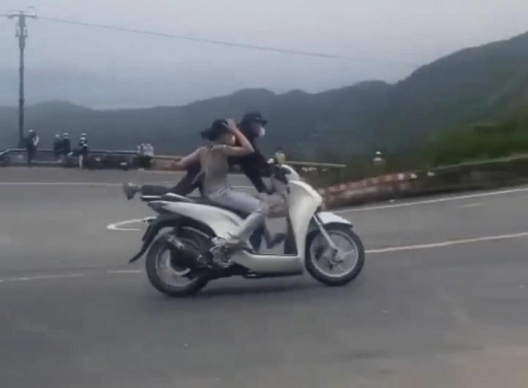 Hai vợ chồng làm xiếc trên xe máy ở đèo Hải Vân bị khởi tố. Ảnh: cắt từ clip.