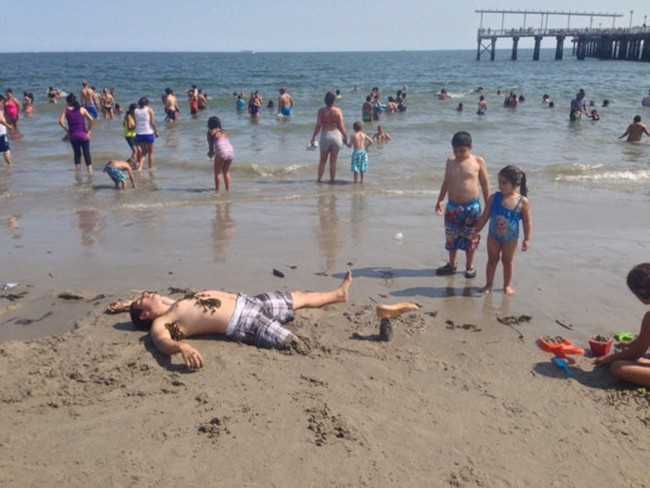 Anh chàng này đang khiến bọn trẻ cảm thấy rất tò mò về cái chân kỳ lạ nhô lên trên cát.
