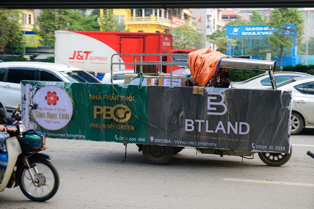 Chiếc xe ba gác chở tấm biển quảng cáo di chuyển trên tuyến đường Khuất Duy Tiến (quận Thanh Xuân, TP Hà Nội)