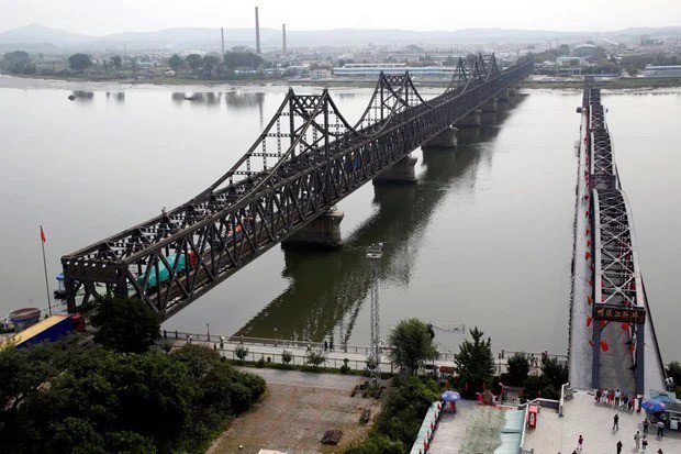 Xe chở hàng hóa đi qua cầu Hữu nghị (trái) từ Đan Đông, Trung Quốc, đến thành phố Sinuiju, Triều Tiên