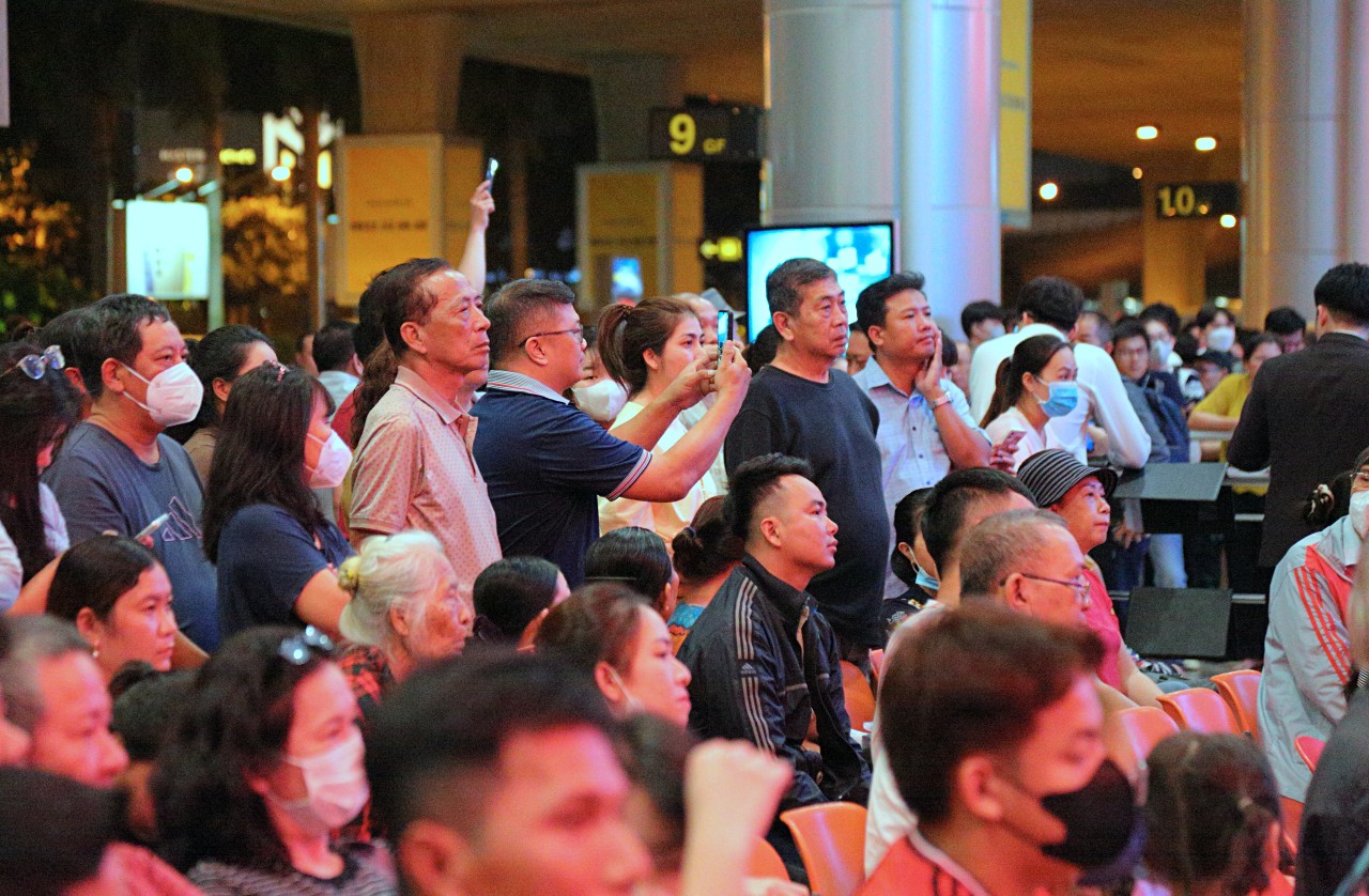 Không khí tại ga đến quốc tế rộn ràng, tấp nập mỗi dịp Tết đến khi hàng nghìn người đến đón Việt kiều. Các hàng ghế chờ đều kín chỗ, kẻ đứng và người ngồi đều tập trung vào màn hình hiển thị thông tin các chuyến bay hạ cánh.