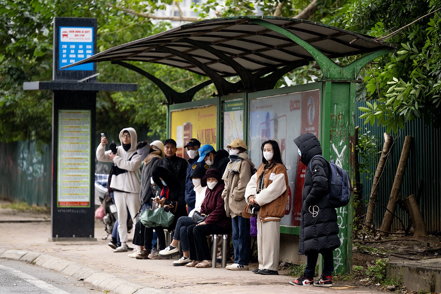  Mọi người mặc áo ấm, khẩu trang, mũ và khăn khi đứng chờ xe buýt trên đường Nguyễn Trãi (quận Thanh Xuân).