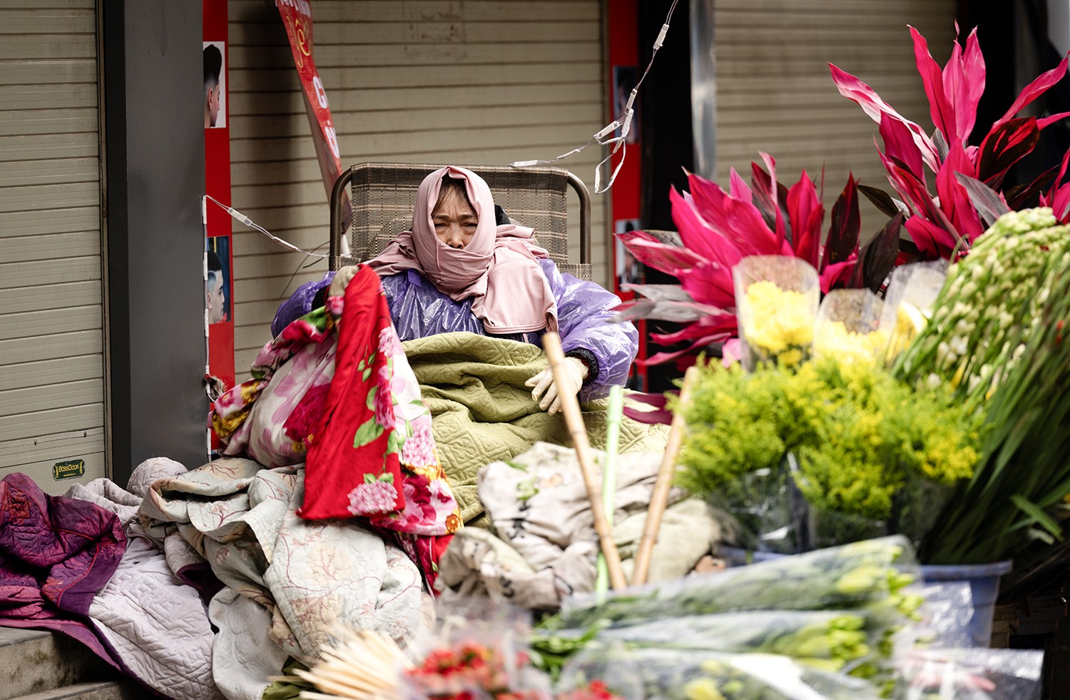 Để chống lại cái lạnh, người phụ nữ bán hoa trên phố Trung Phụng mặc áo ấm, áo mưa và mang thêm bên mình rất nhiều chăn ấm.