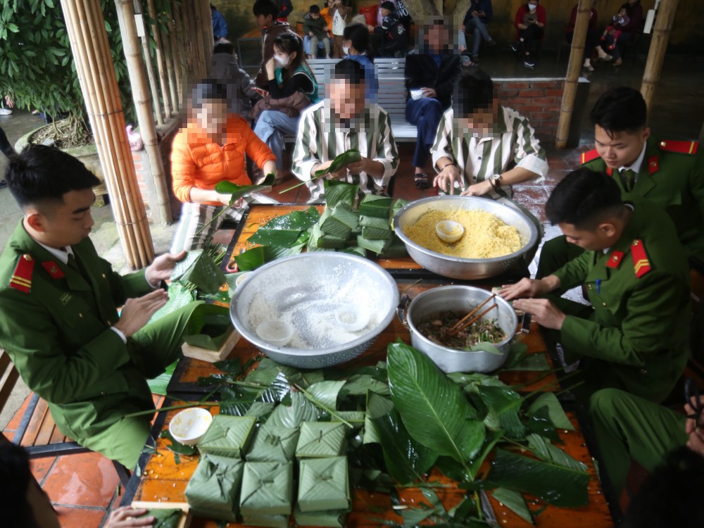 Cán bộ trại tạm giam cùng phạm nhân gói bánh chưng để đón Tết. (Ảnh: Công an tỉnh Hà Tĩnh)