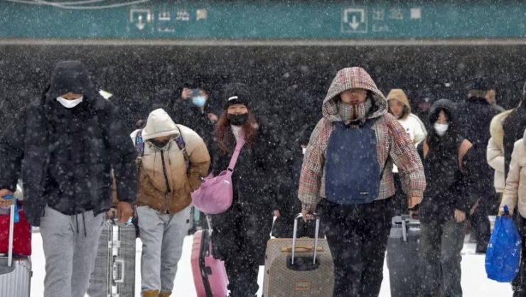 Hành khách rời ga xe lửa ở TP Hoài Bắc, tỉnh An Huy (miền trung Trung Quốc) ngày 4-2 giữa trời tuyết. Ảnh: AP