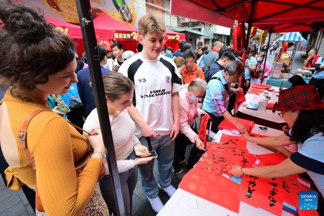Sinh viên nước ngoài xem các nghệ sĩviết thư pháp Trung Quốc ở phố Temple. Ảnh: Tân Hoa Xã