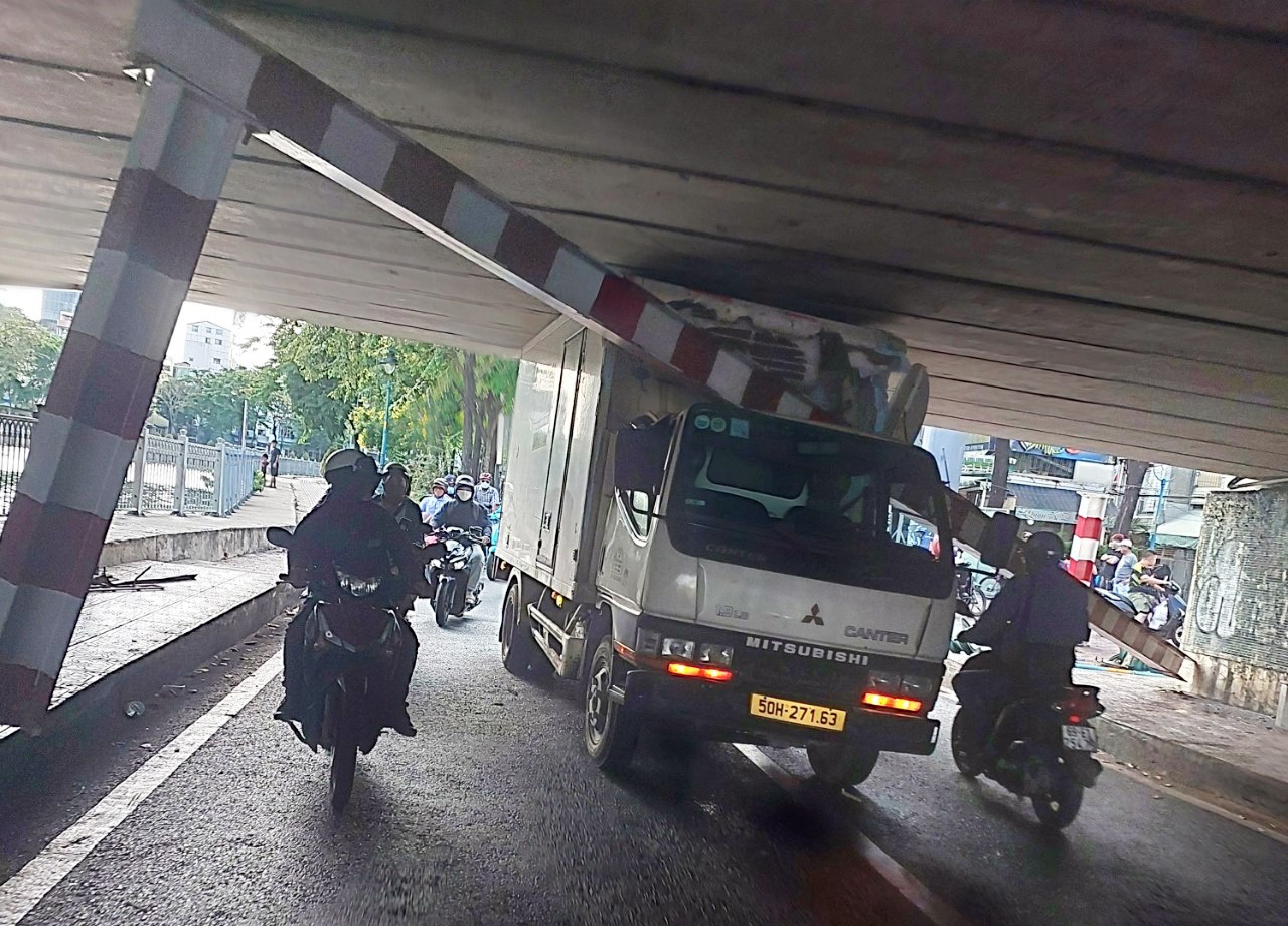 Xe tải kéo gãy thanh chắn giới hạn chiều cao và mắc kẹt dưới gầm cầu