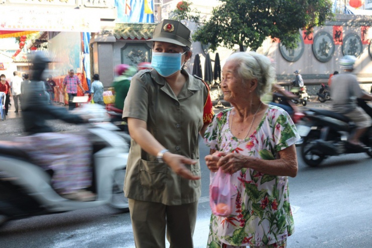 Lực lượng bảo vệ hỗ trợ người lớn tuổi sang đường sau khi đi vay lộc tại chùa Ông.