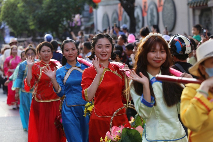 Những cô gái người Hoa gánh thúng hoa diễu hành trên phố.