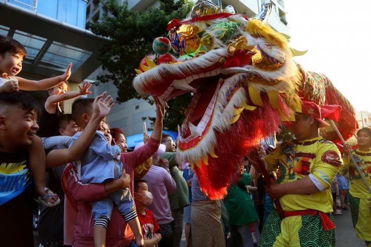 Người dân hai bên đường tranh thủ chạm vào đầu lân cầu may mắn.