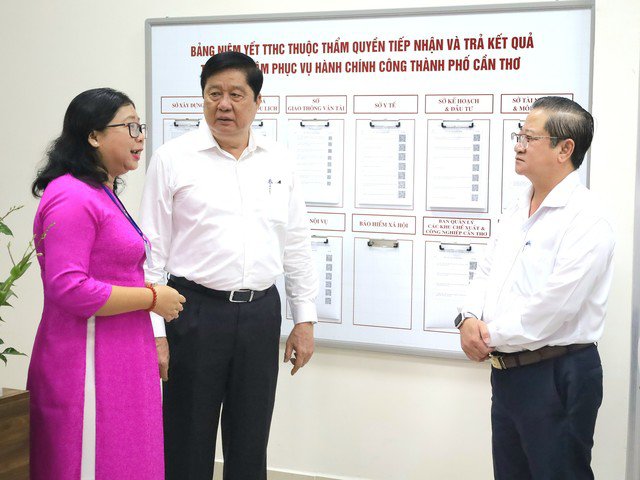 Ông Trần Việt Trường (bìa phải) và ông Phạm Văn Hiểu, Chủ tịch HĐND TP (đứng thứ hai từ trái sang), nghe lãnh đạo trung tâm nói về việc giải quyết thủ tục hành chính cho người dân.