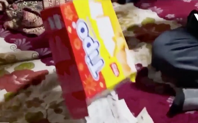 Tiền được đổ ra từ hộp bánh quy mà người này đã cất giấu. (Ảnh: cắt từ clip VTV).