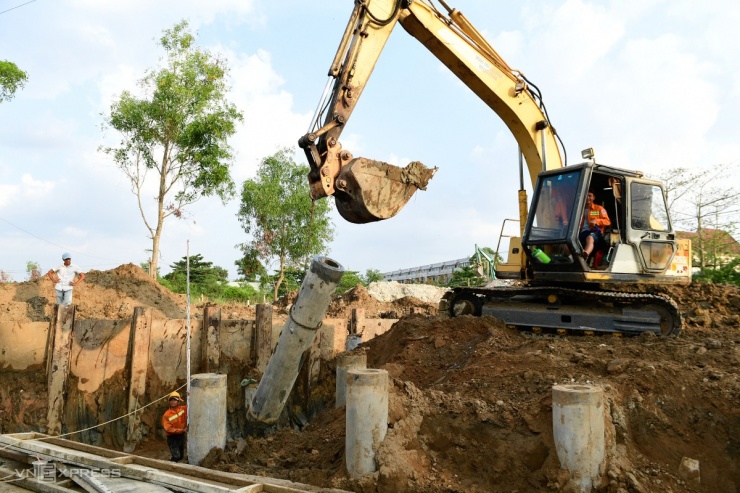 Công nhân dùng máy xúc để ép cọc khu vực nền đất yếu đoạn gần đường Trịnh Quang Nghị, chiều 27/2. Hiện nhiều tổ công nhân, kỹ sư chia thành ba ca, bốn kíp làm việc xuyên suốt sớm đưa dự án về đích.