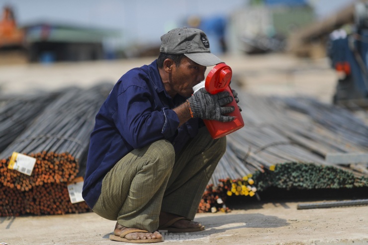 Dưới cái nắng nóng như đổ lửa, công nhân phải uống nước liên tục, thậm chí là rửa mặt trực tiếp dưới vòi nước để hạ nhiệt.