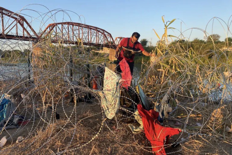 Một người nhập cư trái phép tìm cách vượt qua hàng rào thép gai ở bang Texas để vào Mỹ.