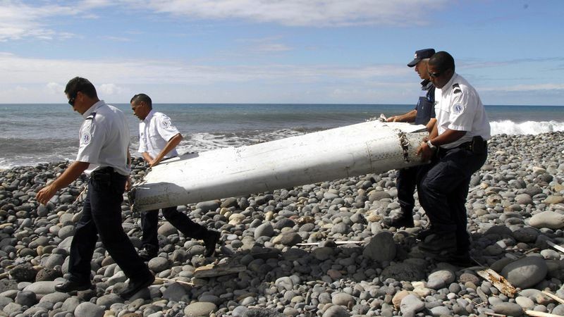 Các sĩ quan mang theo phần cánh phụ của máy bay MH370 được phát hiện ở đảo Reunion. Ảnh: EPA