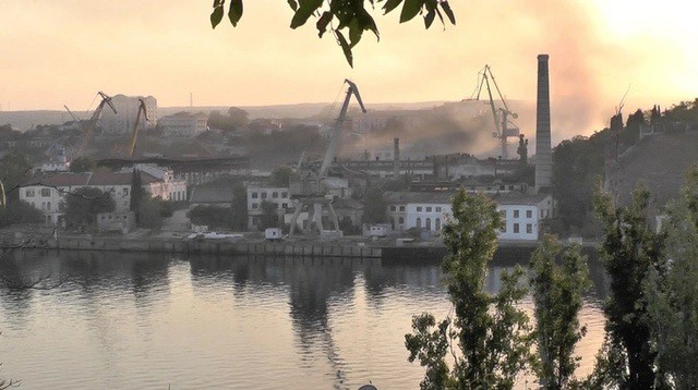 Khói bốc lên từ các xưởng đóng tàu tại TP Sevastopol trên bán đảo Crimea, nghi là bị trúng không kích của Ukraine hôm 13-9-2023. Ảnh: Reuters