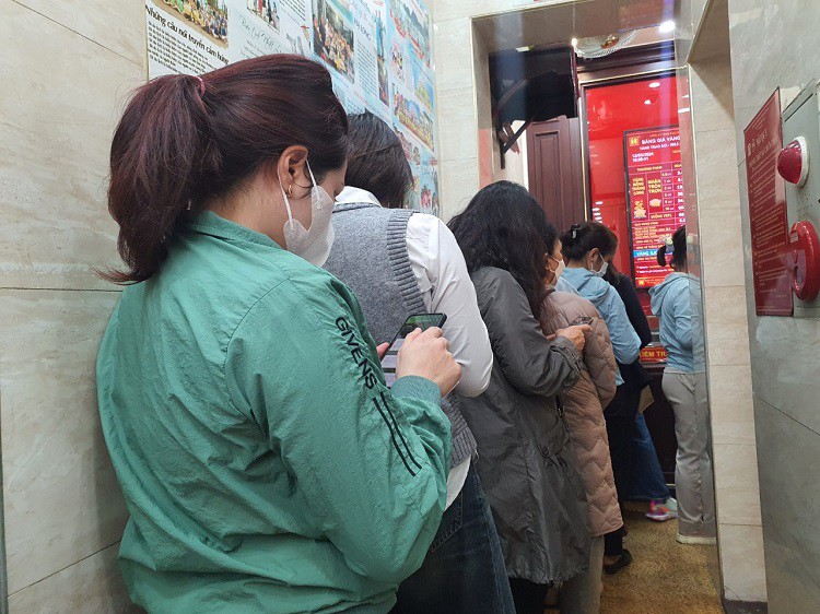 Trước quầy giao dịch, hàng chục khách xếp hàng, đứng nép vào tường, chừa một lối đi nhỏ ở giữa.