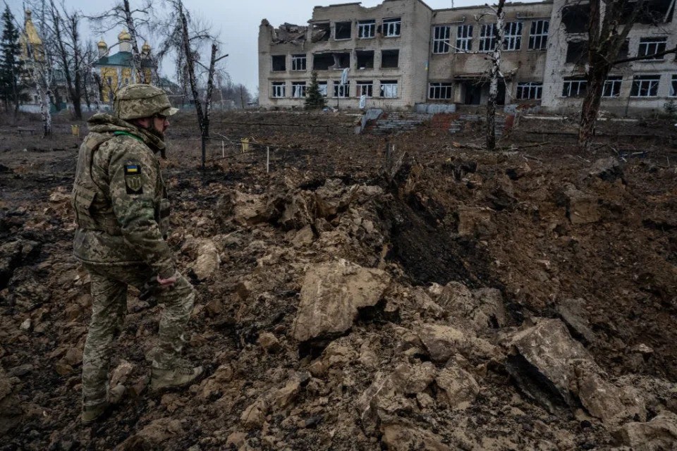 Một binh sĩ Ukraine chứng kiến sự tàn phá do một quả bom lượn Nga gây ra ở Kupiansk vào tháng 2/2024. Ảnh: Getty