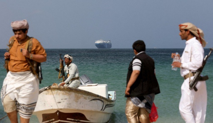 Những người cầm vũ khí đứng trên bãi biển khi tàu thương mại Galaxy Leader bị Houthis bắt giữ và đang neo đậu ngoài khơi bờ biển al-Salif (Yemen) vào hôm 5-12. Ảnh: REUTERS