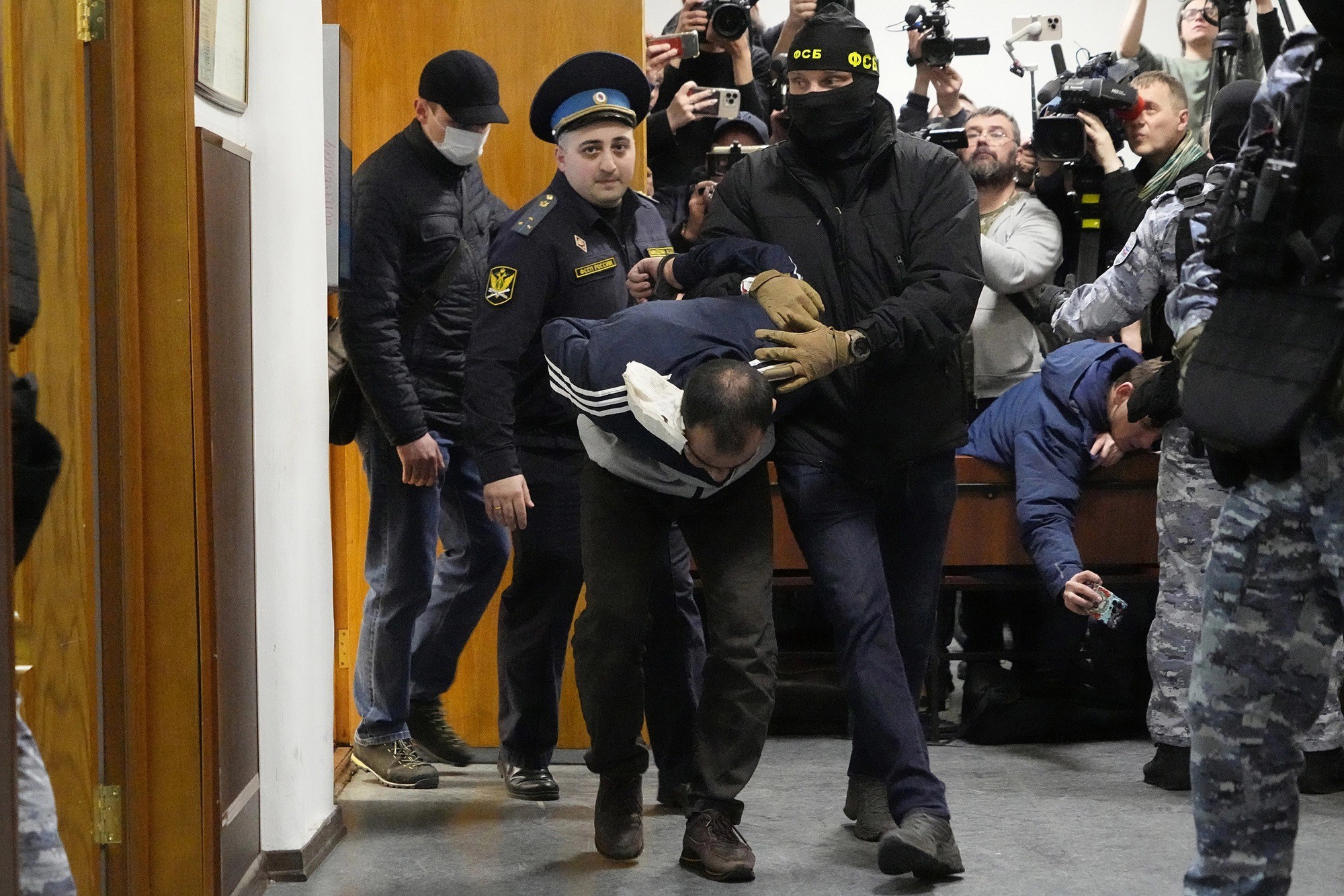 Cảnh sát Nga áp giải một nghi phạm trong vụ khủng bố ở Moscow (ảnh: RT)