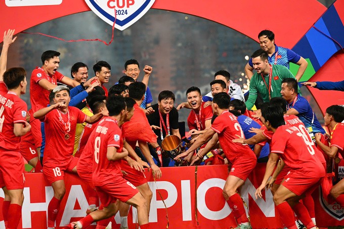 HLV Kim Sang-sik (giữa, áo đen) cùng các học trò chuẩn bị nâng cup vô địch ASEAN Cup trên sân Rajamangala tối 5/1. Ảnh: Hiếu Lương