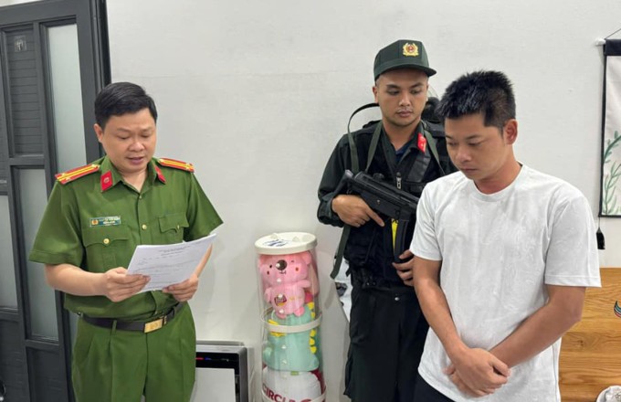 Trần Trung Hiếu (phải) nghe cảnh sát đọc lệnh bắt, khám xét. Ảnh: Công an cung cấp