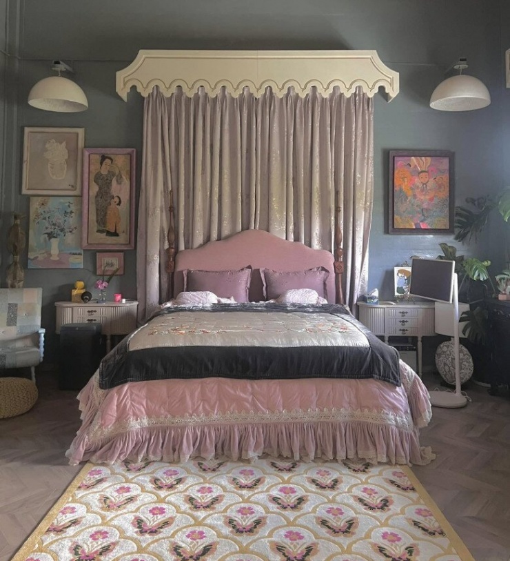 Phòng ngủ của Lý Quí Khánh mang phong cách hoài cổ với gam màu hồng pastel nhẹ nhàng kết hợp cùng rèm lụa ánh kim sang trọng. Chiếc giường lớn với phần đầu giường bọc nỉ mềm mại, chăn gối viền ren tinh tế tạo cảm giác ấm áp. Những bức tranh nghệ thuật treo tường cùng thảm trải sàn hoa văn cổ điển làm tăng thêm vẻ thanh lịch, duy mỹ của không gian.