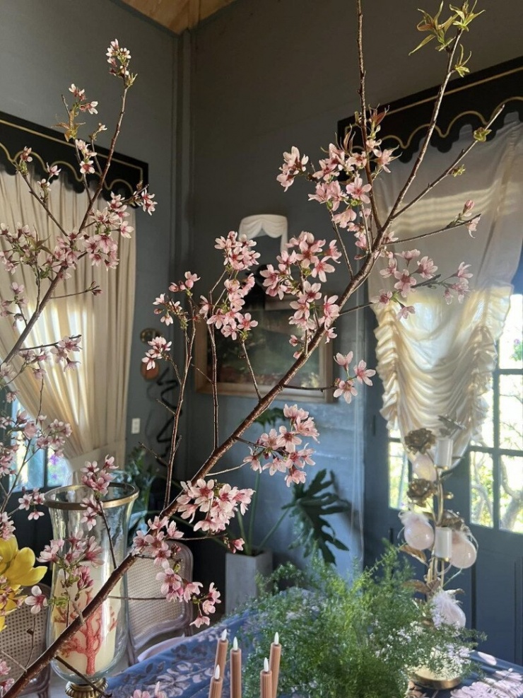 Một góc bàn ăn trong nhà Lý Quí Khánh được trang trí đậm chất thơ với cành hoa đào nở rộ. Nội thất mang phong cách châu Âu cổ điển với rèm buông mềm mại, ánh sáng tự nhiên len lỏi qua khung cửa tạo cảm giác ấm áp, bình yên.