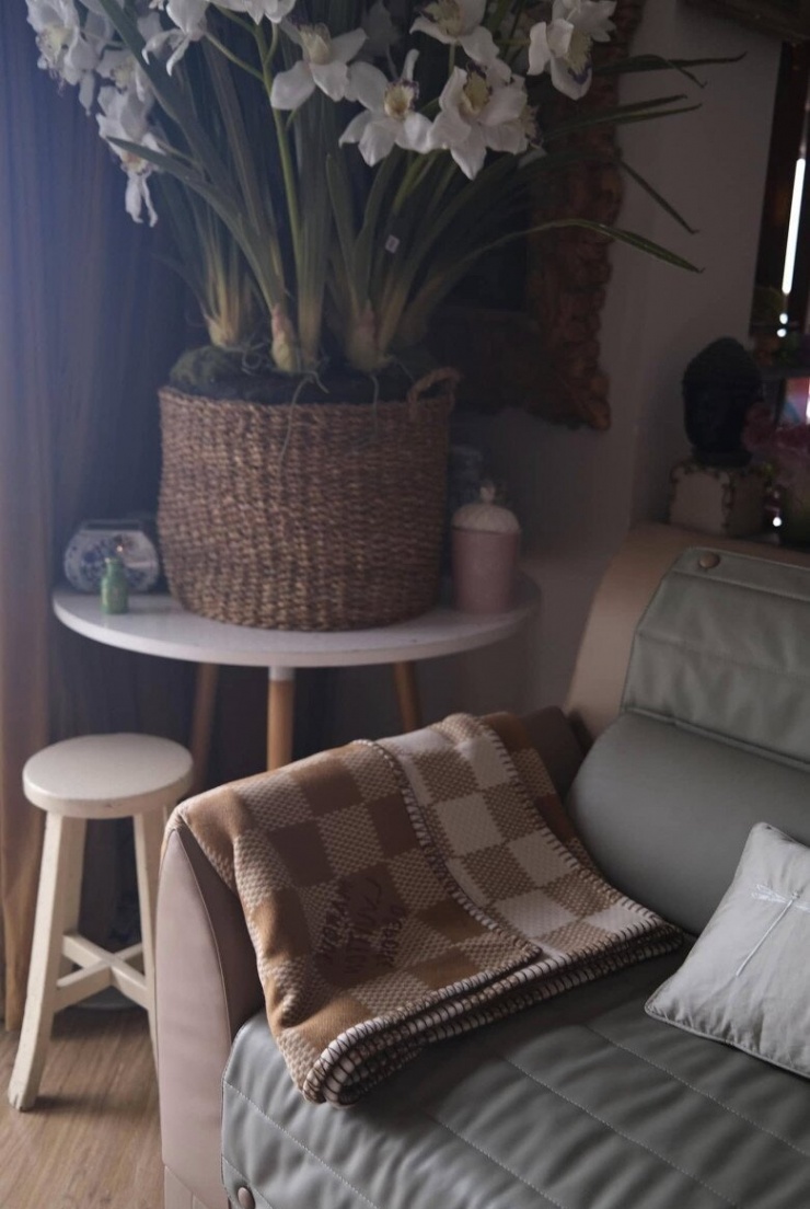 Chiếc sofa da màu rêu với chăn len caro ấm áp, bên cạnh là chậu lan trắng tinh khôi được đặt trong giỏ mây thủ công. Từng chi tiết nhỏ trong căn hộ đều toát lên sự chăm chút, tạo nên một không gian vừa nghệ thuật vừa gần gũi.
