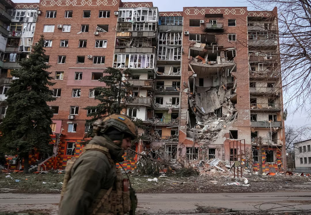 Binh sĩ Ukraine đi qua một tòa nhà bị trúng tên lửa trong cuộc xung đột với Nga (ảnh: Reuters)