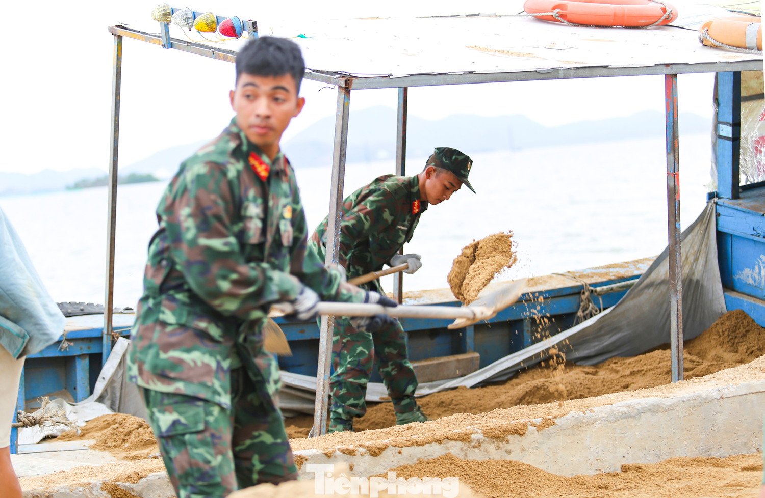 Các chiến sĩ thuộc Quân đoàn 34 hỗ trợ xúc cát lên đò để vận chuyển ra Cồn Chim xây nhà cho người dân bị đổ sập trong bão 13. Ảnh: Trương Định