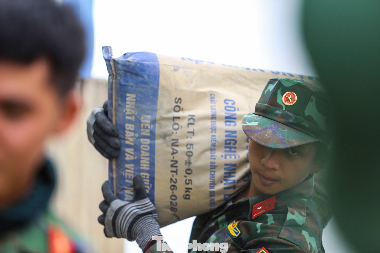 Nhờ sự hỗ trợ tận tình của các chiến sĩ bộ đội trong việc vận chuyển vật liệu, gia đình chị Ngô Thị Mỹ Nhung (38 tuổi, xóm Cồn Chim) mới có thể từng bước dựng lại ngôi nhà bị bão đánh sập. Chị Nhung cho biết, ngoài 60 triệu đồng được Nhà nước hỗ trợ và sự giúp đỡ của người thân, nhà hảo tâm, chính sự chung tay của bộ đội đã giúp gia đình giảm gánh nặng chi phí, sớm có điều kiện ổn định chỗ ở. “Nếu phải thuê vận chuyển bên ngoài, chi phí sẽ tăng lên rất nhiều”, chị chia sẻ. Ảnh: Trương Định