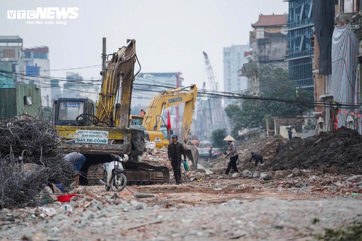 Ghi nhận thực tế, dọc tuyến phố Đê La Thành, mặt bằng sau phá dỡ đang được khẩn trương thu dọn. Máy xúc hoạt động liên tục để thu xà bần, gạch vỡ về một phía, giúp giải phóng không gian. Bên cạnh đó, các công nhân tất bật dọn dẹp thủ công, phối hợp cùng thiết bị cơ giới nhằm làm sạch mặt bằng, phục vụ các bước triển khai tiếp theo của dự án.