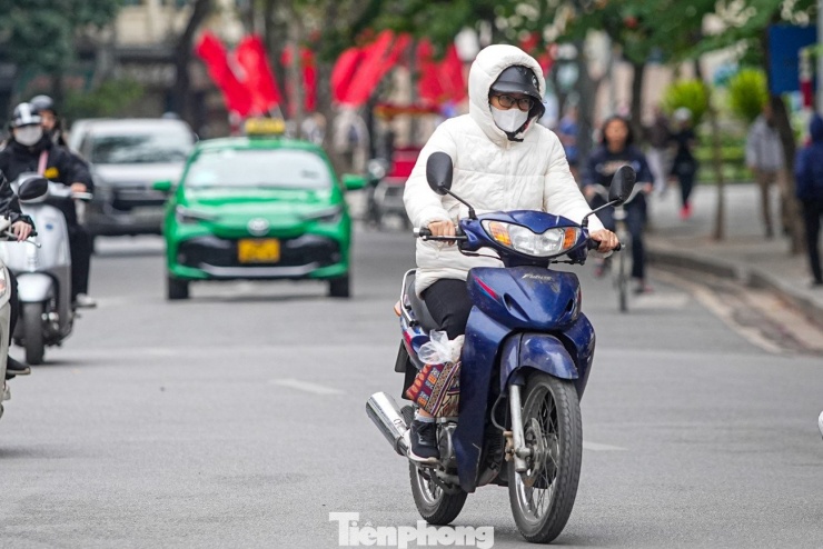 Một người điều khiển xe máy run run trong lớp áo phao.