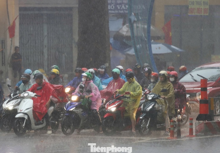 Một số người phải bật đèn xe để di chuyển trong mưa.