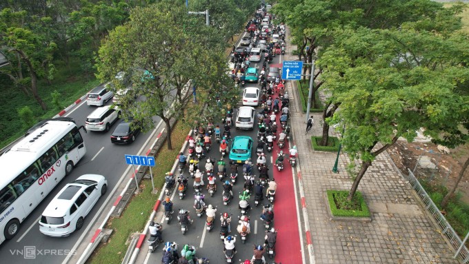Một người đi xe đạp chạy lên vỉa hè trong khi làn ưu tiên bị xe máy "tràn" vào. Ảnh: Đình Văn