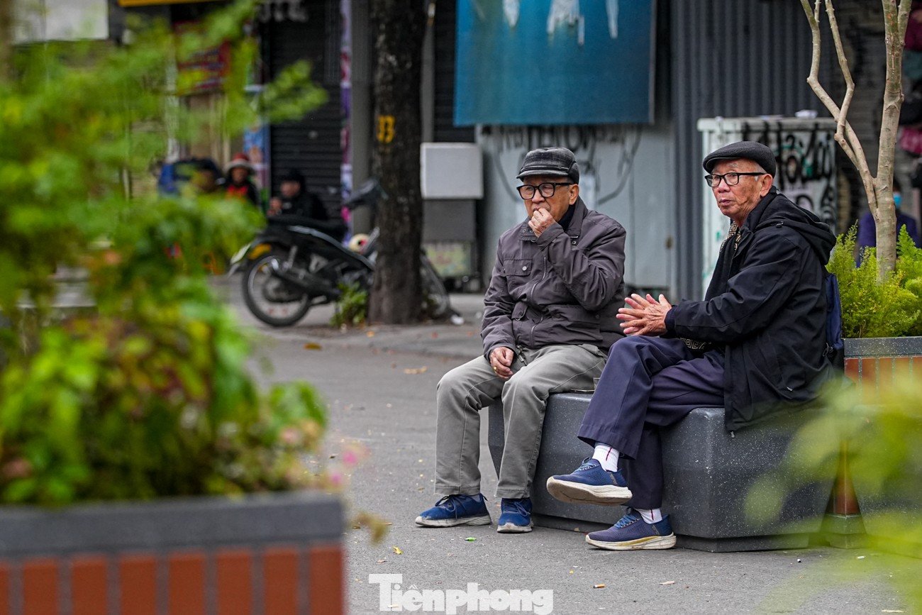 Một số người ngồi run run bên vỉa hè, quán nước.