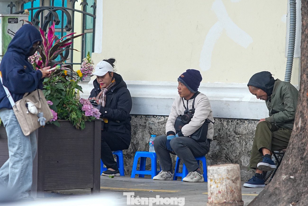 Một số người ngồi run run bên vỉa hè, quán nước.