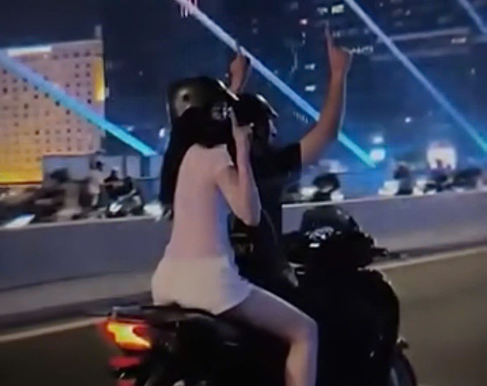 Đôi nam nữ chỉ tay lên trời trên cầu Ba Son.