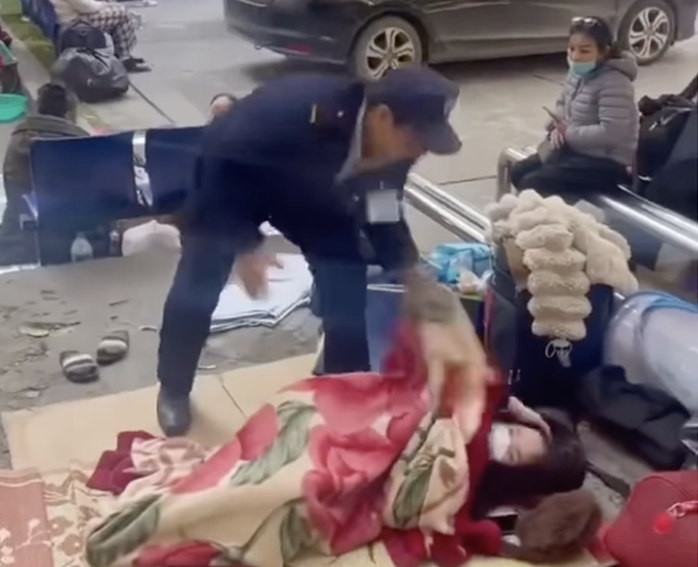 Bảo vệ Bệnh viện Bạch Mai "giật chăn" của người nhà bệnh nhân khi nằm tại khuôn viên bệnh viện - Ảnh: Chụp màn hình