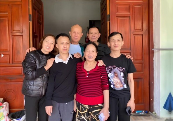 Anh Hoàng (thứ hai từ trái sang) chụp ảnh lưu niệm bên mẹ (áo đỏ) và người thân, tháng 11/2025. Ảnh gia đình cung cấp