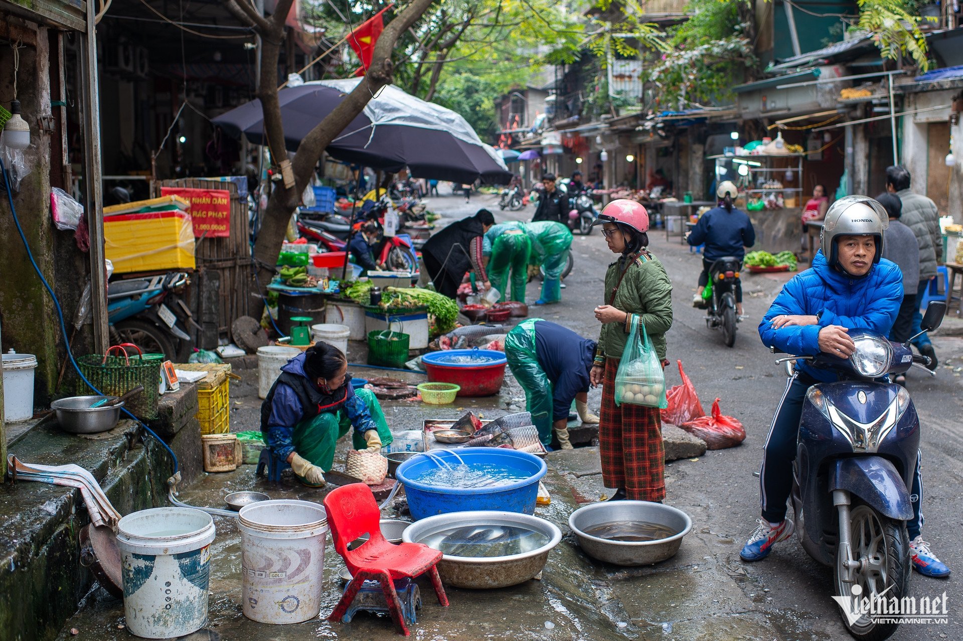 Các sạp hàng kinh doanh rau xanh, hoa quả, thịt, cá và nhiều mặt hàng thực phẩm khác được bày bán nhếch nhác dọc tuyến đường, kéo dài liên tục và chiếm dụng gần như toàn bộ phần vỉa hè dành cho người đi bộ.