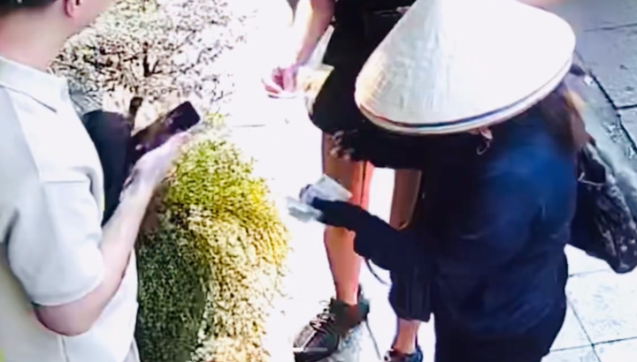 Hình ảnh người phụ nữ bán hàng rong cầm 2 tờ tiền 500.000 đồng của du khách.