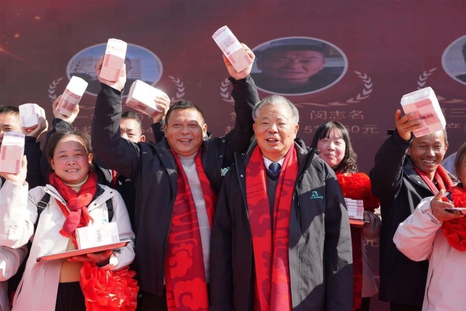 Ông Lăng Kế Hà (thứ ba từ trái sang), chụp ảnh kỷ niệm cùng các nông dân nhận thưởng Tết hôm 9/1 tại công ty Nông nghiệp Xanh ở tỉnh Giang Tây. Ảnh: China News