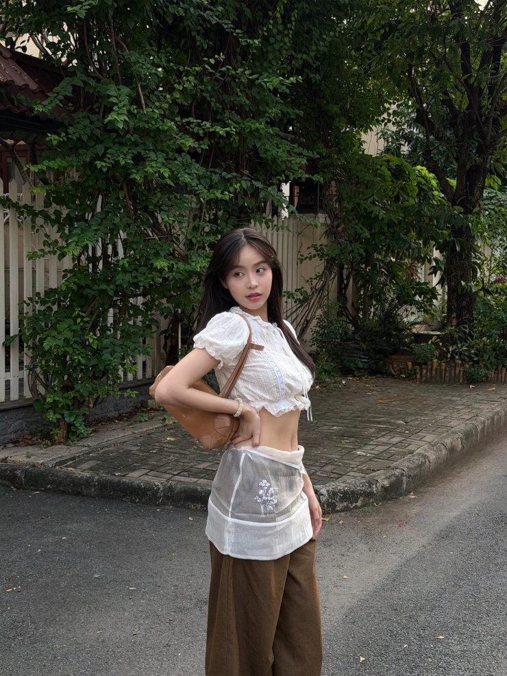Mới đây, nàng hậu quê Đà Nẵng chia sẻ hình ảnh diện áo croptop trắng kết hợp cùng quần ống rộng màu nâu trầm. Thiết kế áo tay phồng nhẹ mang hơi hướng vintage nhưng điểm khiến fan sắc đẹp chú ý là khoe vòng eo siêu nhỏ, siêu cuốn hút của Thanh Thủy.