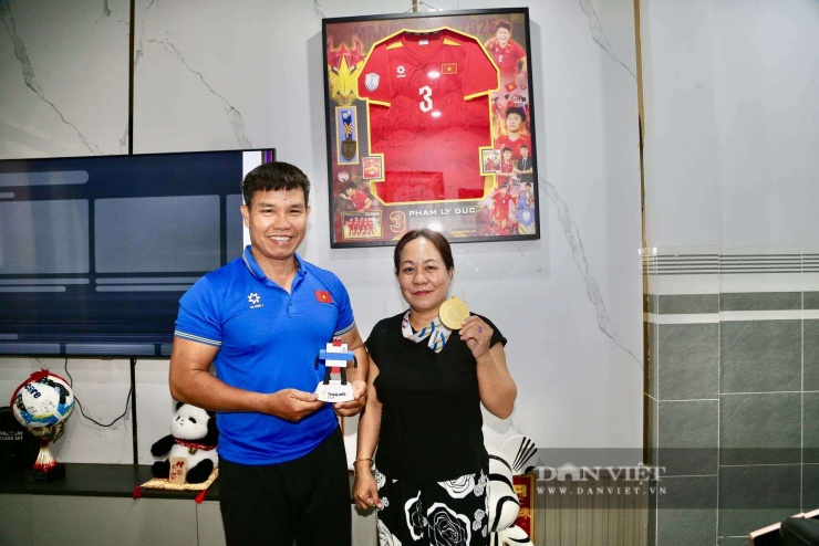 Ba mẹ Phạm Lý Đức cùng chiếc HCV và linh vật SEA Games 33 mà con trai mang về. Phía sau là chiếc tivi "sọc" màn hình vì vỡ một góc. Ảnh: LG