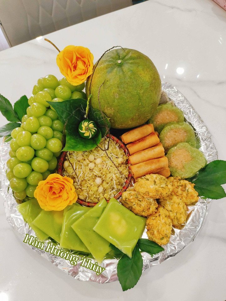 Mâm lễ tạ mùng 1 tháng Chạp có bánh cốm, xôi cốm, bánh chưng, nem rau củ, đậu phụ thì là và hoa trái.