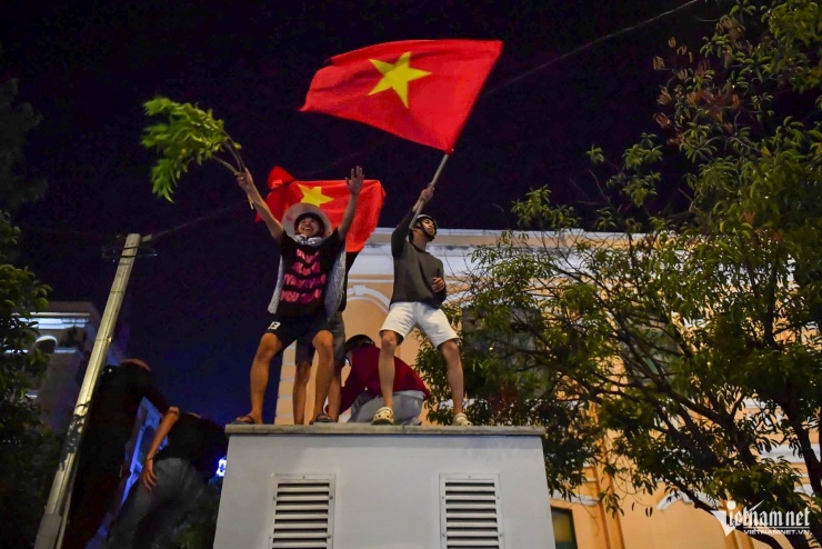 Nhiều thanh niên đứng cả lên trụ điện, hò reo, giương cờ khuấy động không khí.