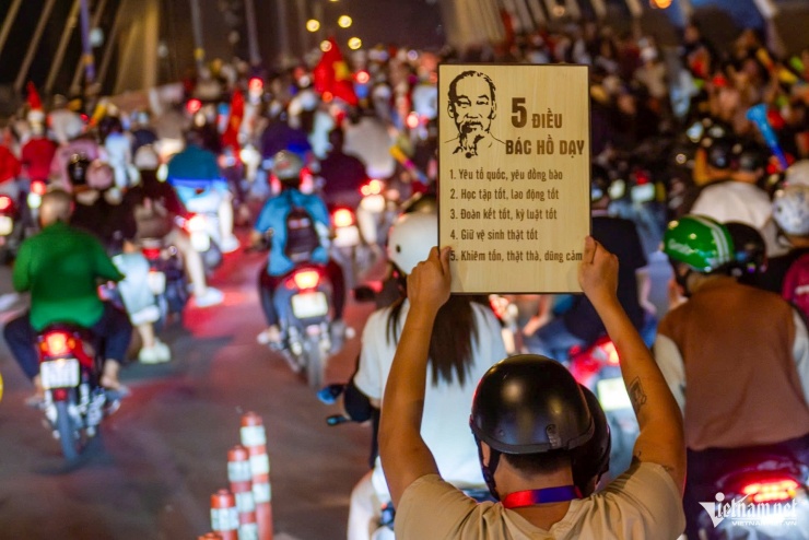 Bạn trẻ giơ cao tấm bảng "5 điều Bác Hồ dạy" xuống đường cổ vũ.&nbsp;